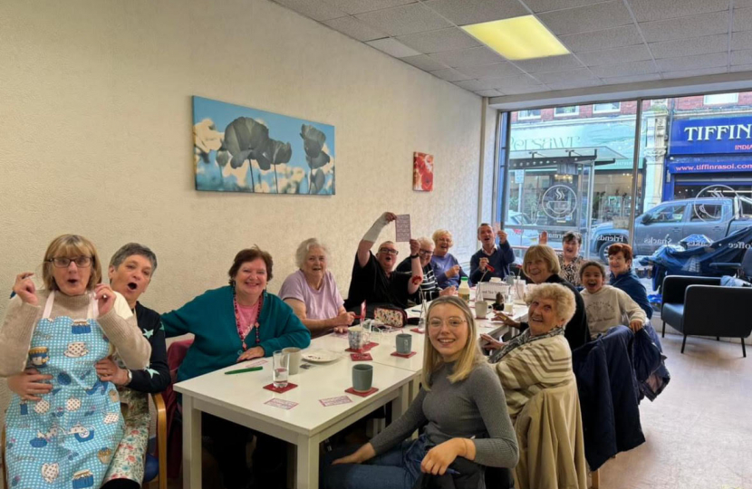 Alun Cairns visiting a table full of people from Age Connects