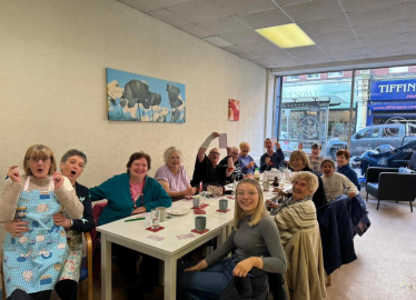 Alun Cairns visiting a table full of people from Age Connects